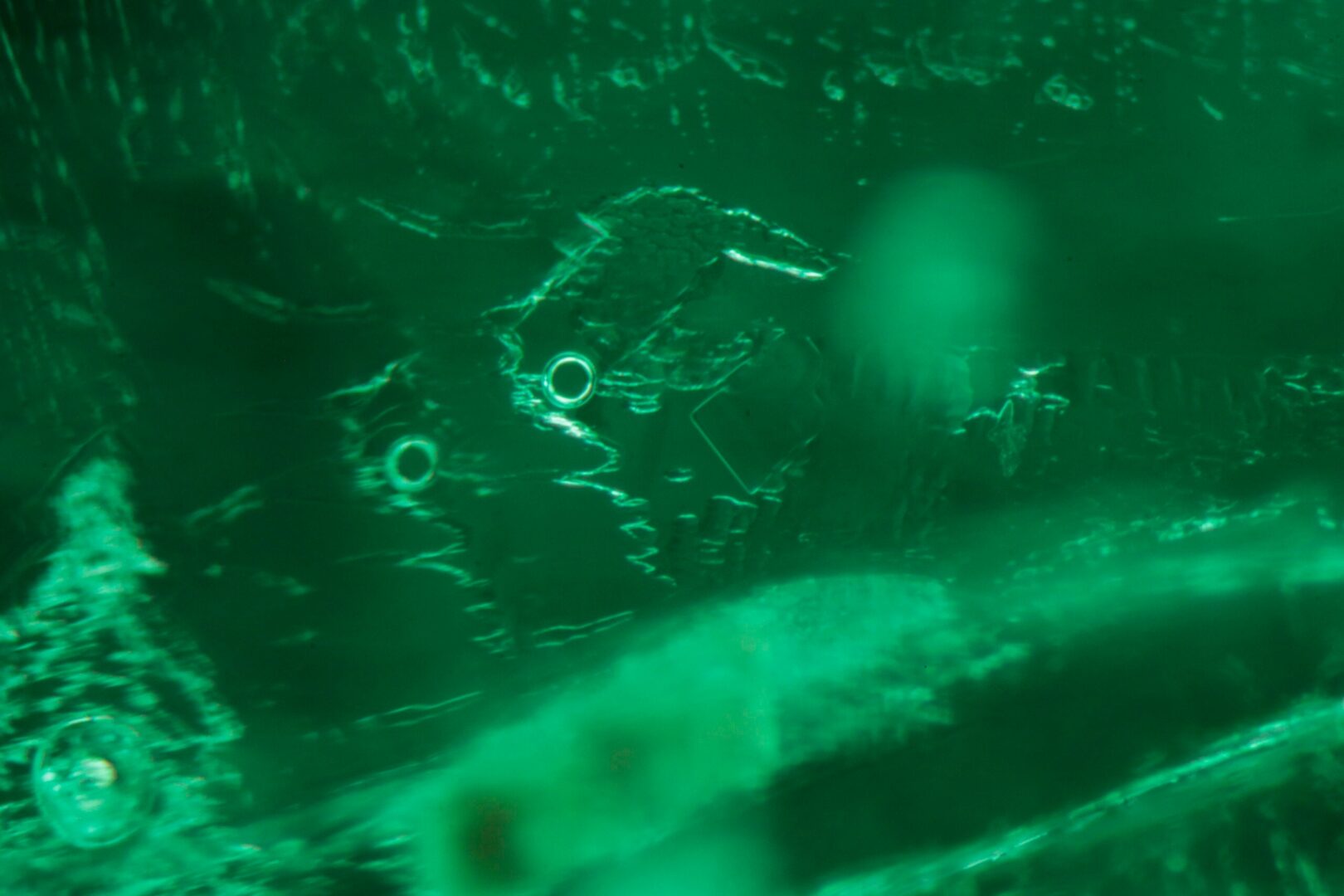 Three-phase inclusion in a Colombian emerald, with a jagged outline, a gas bubble and a cubic crystal, at 2 mm.