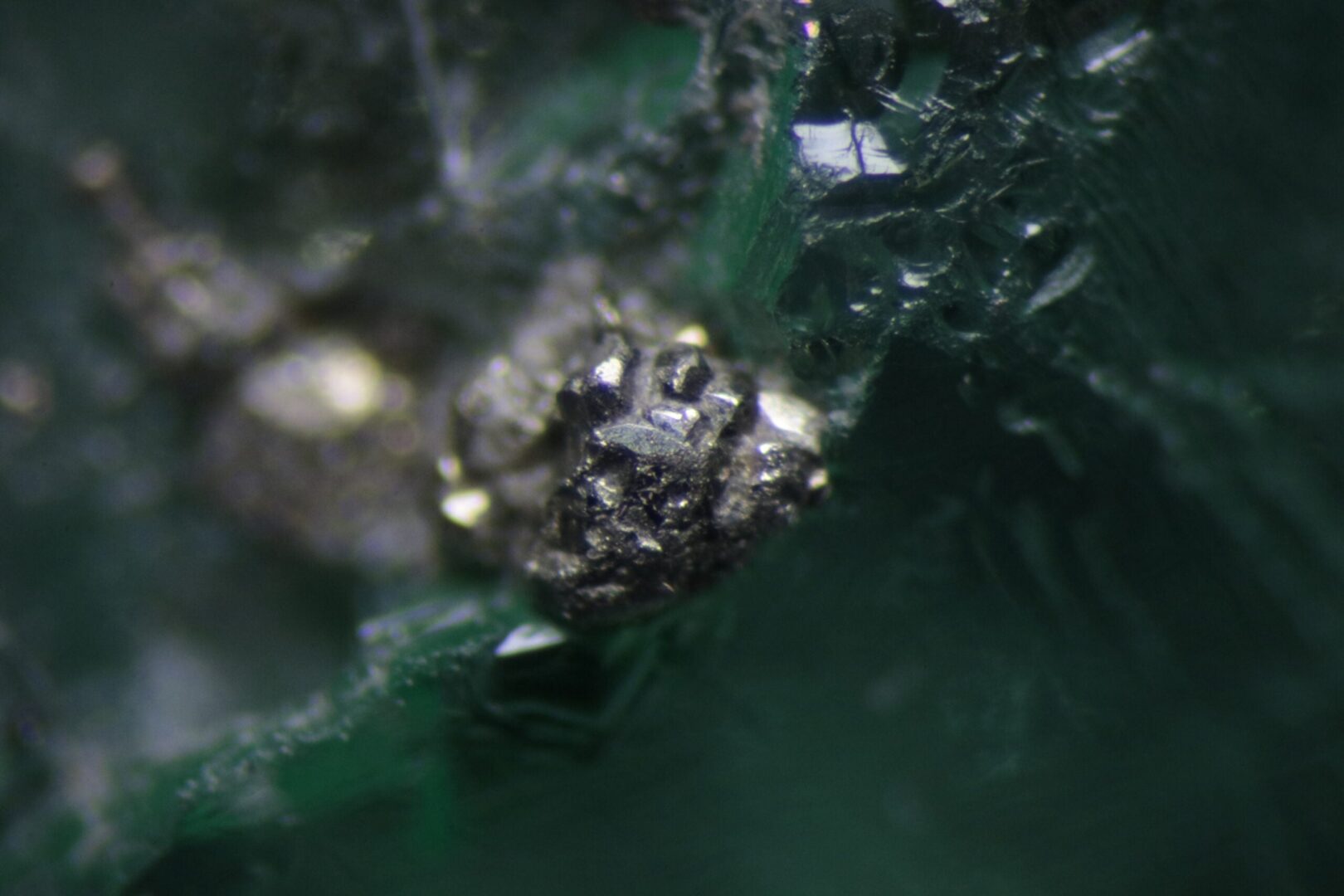 Brassy pyrite crystals in a Colombian emerald, isolated and in clusters, at about 2 mm.
