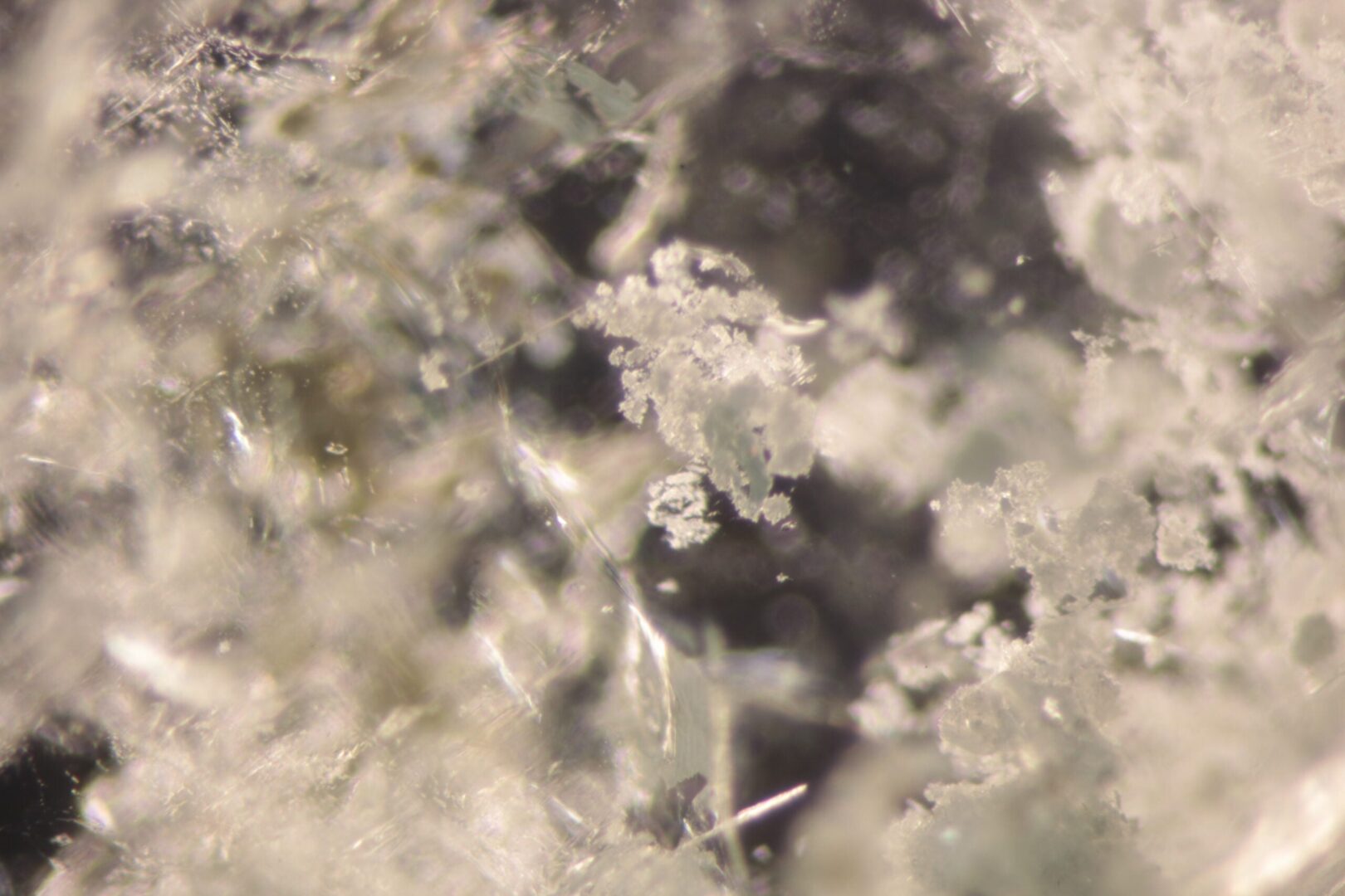 Colourless irregular carbonate crystals in a Colombian emerald, in a flake-like arrangement, at 3 mm.
