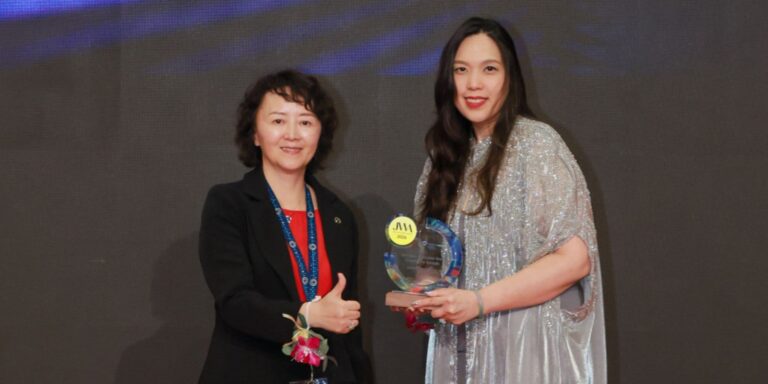 Amira Hatta receiving her NextGen Coloured Gem Excellence Award on stage at JGW Hong Kong, 16 September 2026.
