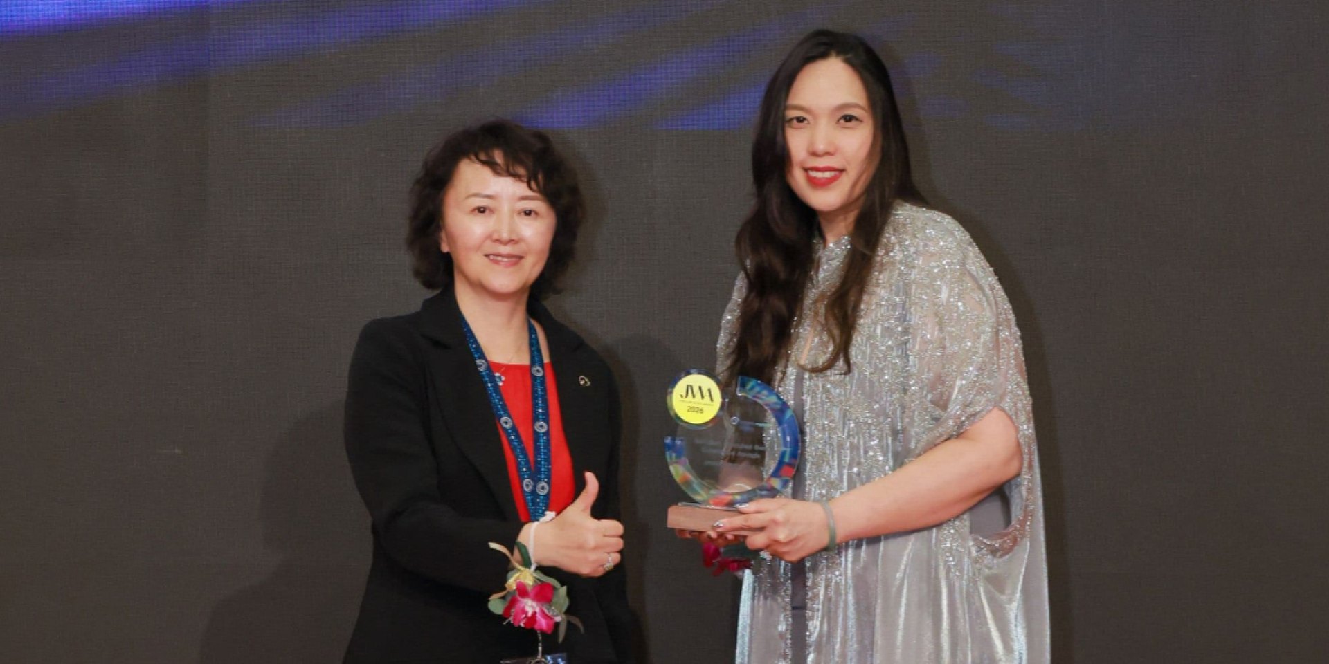 Amira Hatta receiving her NextGen Coloured Gem Excellence Award on stage at JGW Hong Kong, 16 September 2026.